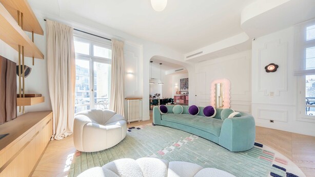 Ein modernes Wohnzimmer mit einer Couch, einem runden Sessel und einem großen Fenster.