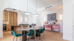 Ein stilvoller Essbereich mit einem runden Tisch, blaugrünen Stühlen und Pendelleuchten.