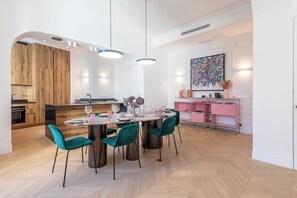 A modern dining area with a round table, teal chairs, and pendant lighting. - Exceptional Family Apartment 8P A/c- Victor Hugo (Paris)