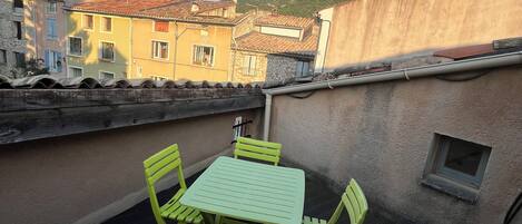 Eine Dachterrasse mit Tisch und Stühlen, mit Blick auf eine gebirgige Landschaft.