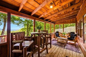 Eine Holzterrasse mit Tisch und Stühlen mit Blick auf ein bewaldetes Gebiet.