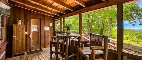 A wooden cabin with a deck, a dining table, and chairs.