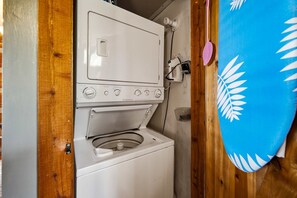 Eine kompakte, weiße Waschmaschine mit Frontlader, platziert in einem kleinen, geschlossenen Raum mit Holzwänden.