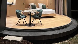 A modern, circular room with a bed, two chairs, and a small table. - Oomi (Barbaste)