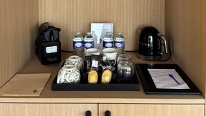 A kitchenette with a coffee maker, water bottles, a mug, and a tray with food items. - Oomi (Barbaste)