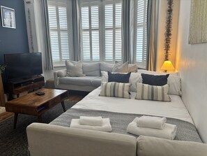 Ein Wohnzimmer mit Sofa, Fernseher, Couchtisch und Lampe.