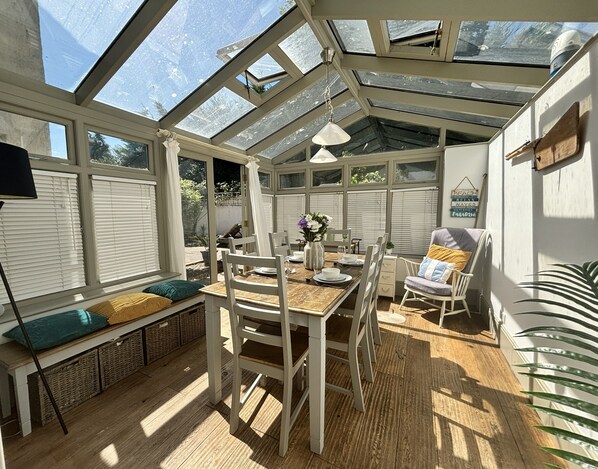 A conservatory with a dining table, chairs, and a bench. - Shipside Village Location
Calm & relaxing Eastbourne apartment & private garden (Eastbourne)