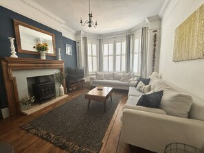 A living room with a fireplace, a sofa, a coffee table, and a television. - Shipside Village Location
Calm & relaxing Eastbourne apartment & private garden (Eastbourne)
