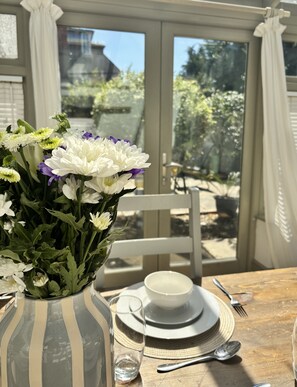 A dining table with a white vase of flowers, a bowl, and cutlery. - Shipside Village Location
Calm & relaxing Eastbourne apartment & private garden (Eastbourne)