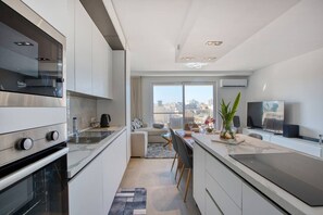 A modern kitchen with a built-in oven, a dining area with a view, and a living space with a TV.