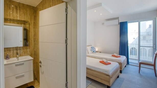 Quarto de hotel com banheiro, cama, janela e varanda.