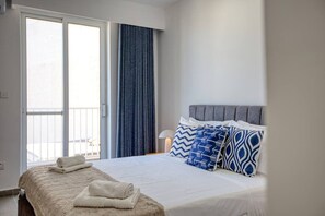 Ein Hotelzimmer mit Bett, Balkon und einem Vorhangfenster.