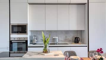Une cuisine moderne dotée d’appareils électroménagers intégrés, un coin repas avec un plan de travail en marbre et une petite plante en pot.