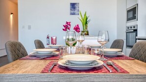 Mesa posta com pratos, copos e talheres, com um vaso de flores ao centro.