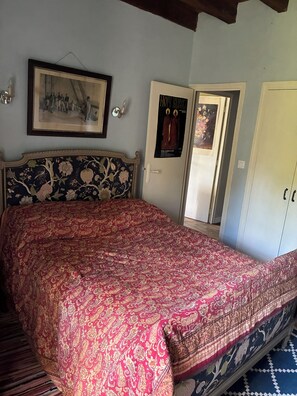 A bedroom with a bed, a framed picture on the wall, and a door with a poster. - The tranquility of rural France!  A charming cottage attached to an old farmhouse. (Uzech)
