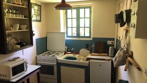 A compact kitchen with a stove, sink, and microwave. - The tranquility of rural France!  A charming cottage attached to an old farmhouse. (Uzech)