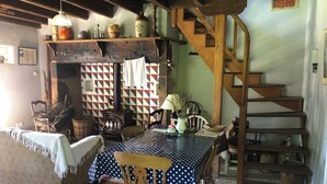 A rustic interior with a wooden staircase, a dining table with a polka dot tablecloth, and a vintage stove. - The tranquility of rural France!  A charming cottage attached to an old farmhouse. (Uzech)