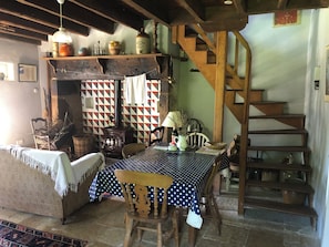 A rustic interior with a wooden staircase, a dining table with a polka dot tablecloth, and a vintage stove.