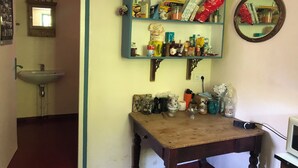 A kitchen with a sink, a wooden table, and shelves stocked with various food items and kitchenware. - The tranquility of rural France!  A charming cottage attached to an old farmhouse. (Uzech)