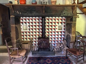 A traditional room with a fireplace, wooden furniture, and a patterned wall. - The tranquility of rural France!  A charming cottage attached to an old farmhouse. (Uzech)