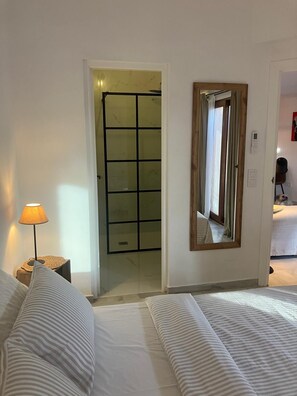 Et hotelværelse med en seng, en sengetavle, et spejl og en dør til et badeværelse.