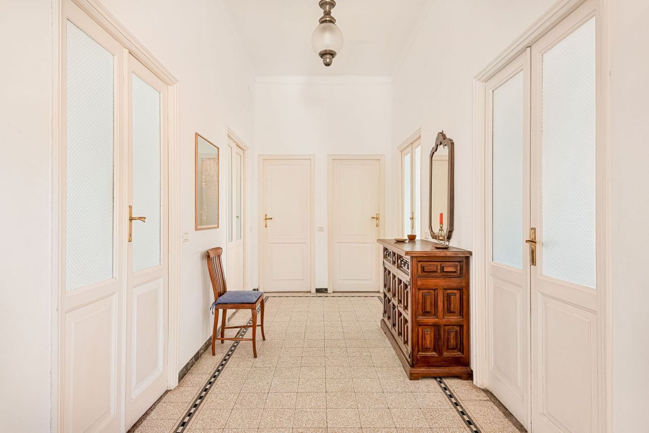 Un couloir avec une chaise en bois, une armoire en bois et un miroir accroché au mur.