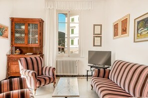 Ein Wohnzimmer mit gestreiften Sofas, einem Holzkabinett, einem Fernseher und gerahmten Bildern an der Wand.