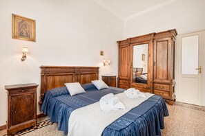 Ein Hotelzimmer mit einem großen hölzernen Bett, einem Kleiderschrank, einem Nachttisch und einer Wandleuchte.