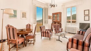 Una sala de estar con una mesa de comedor, sillones a rayas, un sofá, una araña y un televisor.