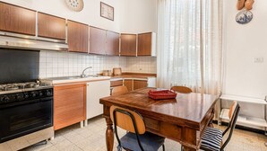 Una cocina con armarios de madera, estufa y una mesa de comedor con sillas.