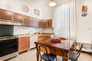 A kitchen with wooden cabinets, a stove, and a dining table with chairs.
