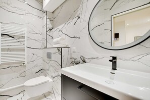 A bathroom with a toilet, a sink, and a mirror. - Cosy Modern Flat 1BR 4P Oberkampf (Paris)