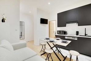 A modern kitchen with dark cabinets, a microwave, and a coffee machine. - Cosy Modern Flat 1BR 4P Oberkampf (Paris)