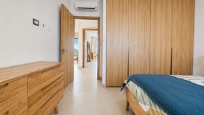 Ein Schlafzimmer mit einem Holzschrank, einem Bett mit blauer und weißer Bettdecke und einem Flur, der zu einem Balkon führt.