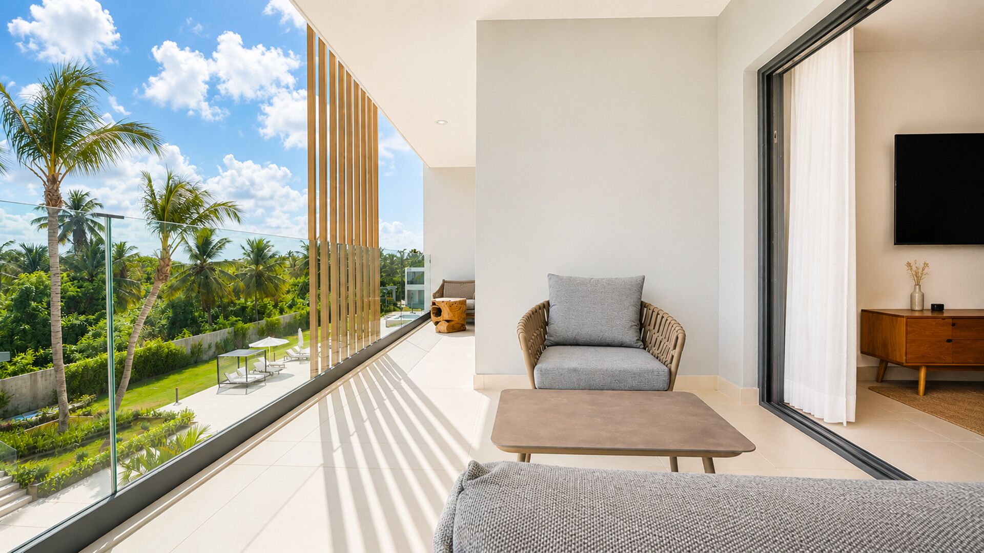 A modern living room with a balcony overlooking a tropical garden.