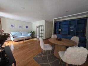 A living room with a light blue sofa, a round wooden table with chairs, a blue bookshelf, and a white fluffy chair. - Beautiful, bright apartment in the port of Ferrol (Ferrol)