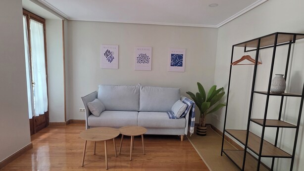 A living room with a grey sofa, two small round tables, a potted plant, and a black metal shelving unit. - Beautiful, bright apartment in the port of Ferrol (Ferrol)