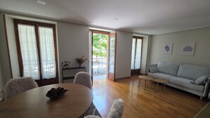 A dining area with a round table and chairs, a sofa, and a view through a glass door to an outdoor area. - Beautiful, bright apartment in the port of Ferrol (Ferrol)