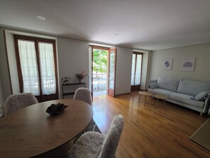 A dining area with a round table and chairs, a sofa, and a view through a glass door to an outdoor area. - Beautiful, bright apartment in the port of Ferrol (Ferrol)
