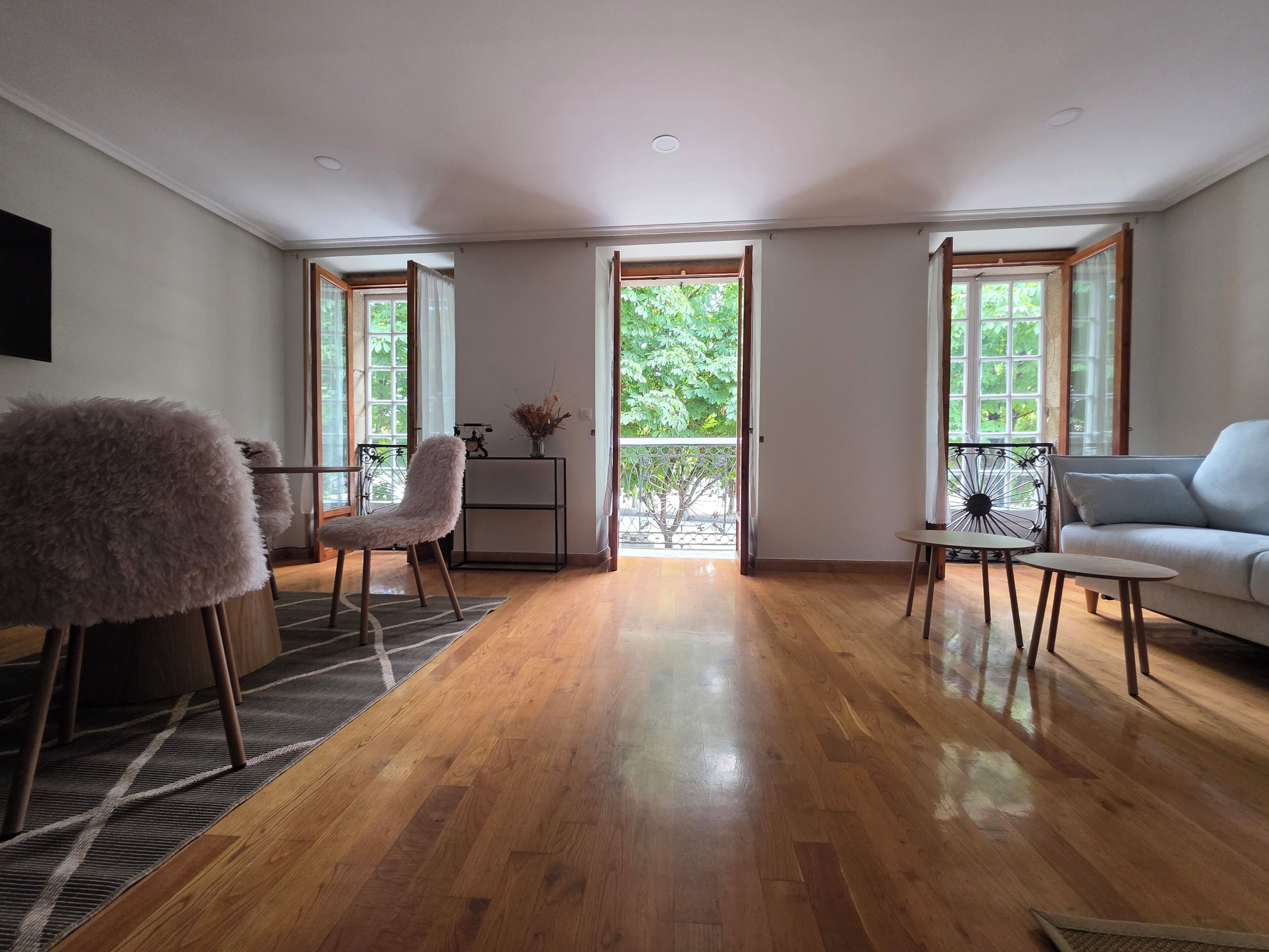 Ein geräumiger Wohnbereich mit Holzboden, einem flauschigen Sessel, einer Couch und einem kleinen Tisch.