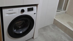 A Samsung washing machine in a laundry room with white cabinets and a tiled floor. - Beautiful, bright apartment in the port of Ferrol (Ferrol)