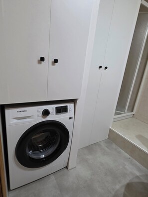 A Samsung washing machine in a laundry room with white cabinets and a tiled floor. - Beautiful, bright apartment in the port of Ferrol (Ferrol)