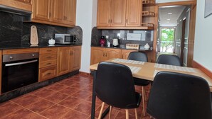 A kitchen with wooden cabinets, a microwave, a coffee maker, and a dining table with chairs. - Beautiful, bright apartment in the port of Ferrol (Ferrol)
