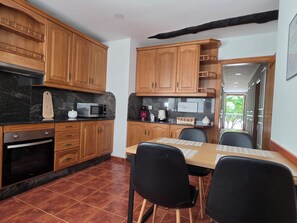 A kitchen with wooden cabinets, a microwave, a coffee maker, and a dining table with chairs. - Beautiful, bright apartment in the port of Ferrol (Ferrol)