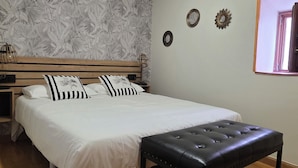 A bedroom with a bed, a wooden bench, a nightstand, and a wall with decorative items. - Beautiful, bright apartment in the port of Ferrol (Ferrol)
