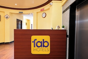 Una mesa de recepción con un cartel de 'fab hotels', un reloj y un letrero de 'no fumar' en la pared.