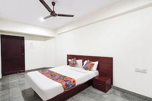 Un dormitorio con cama, mesita de noche, cabecera de madera, ventilador de techo y una puerta.