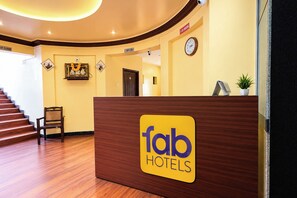 En receptionsdisk med en skylt som visar namnet på hotellkedjan, en klocka och en skylt med texten ”rökning förbjuden” på väggen.