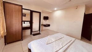 Una habitación de hotel con una cama, un armario, un televisor montado en la pared y una puerta que da a otra habitación.