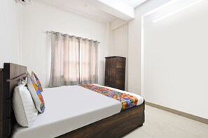 A bedroom with a bed, curtains, a wardrobe, and a window. - Fabhotel Jk Inn (Jaipur)